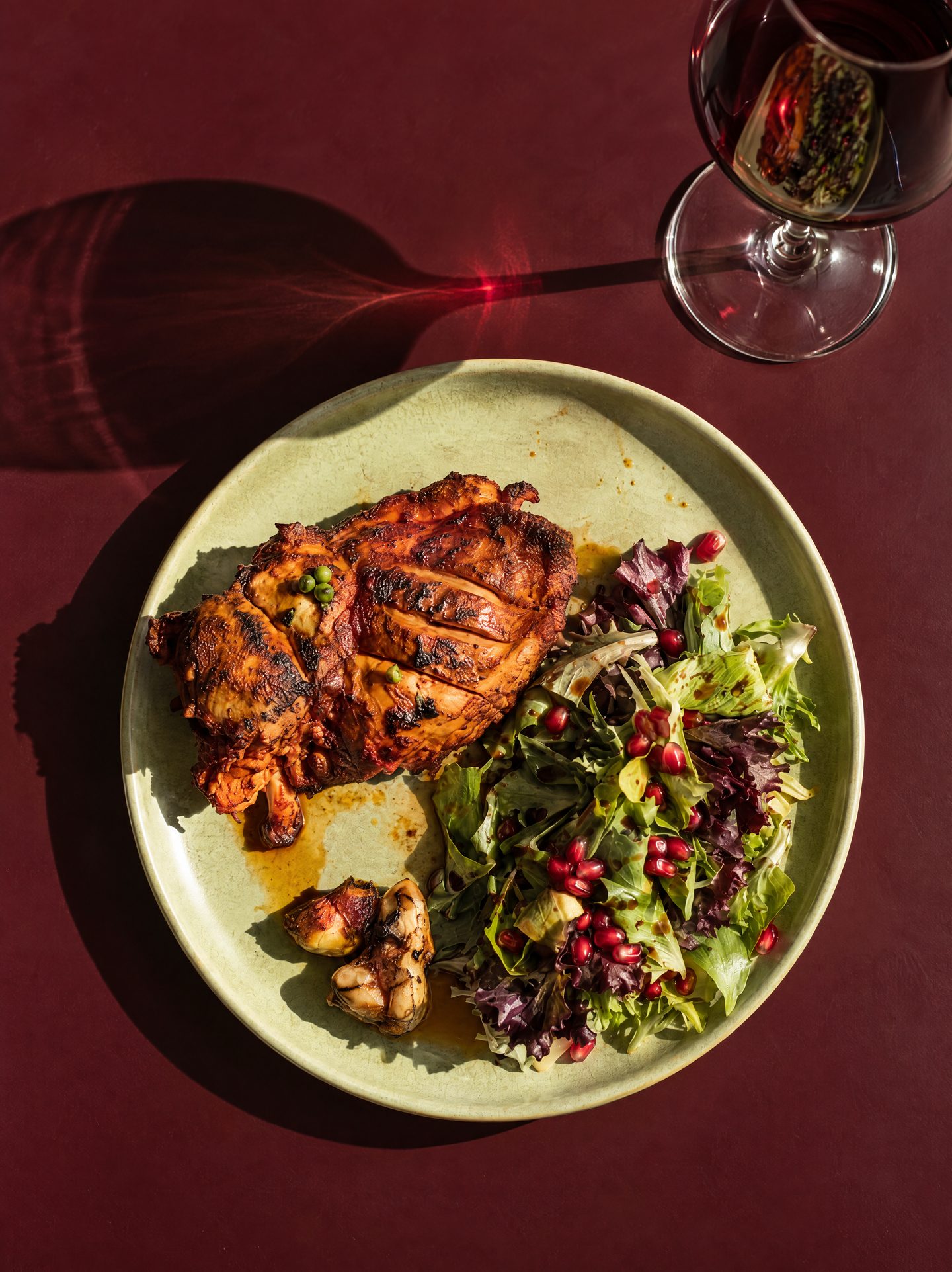 Charcoal-grilled chicken with a pomegranate salad on a green plate