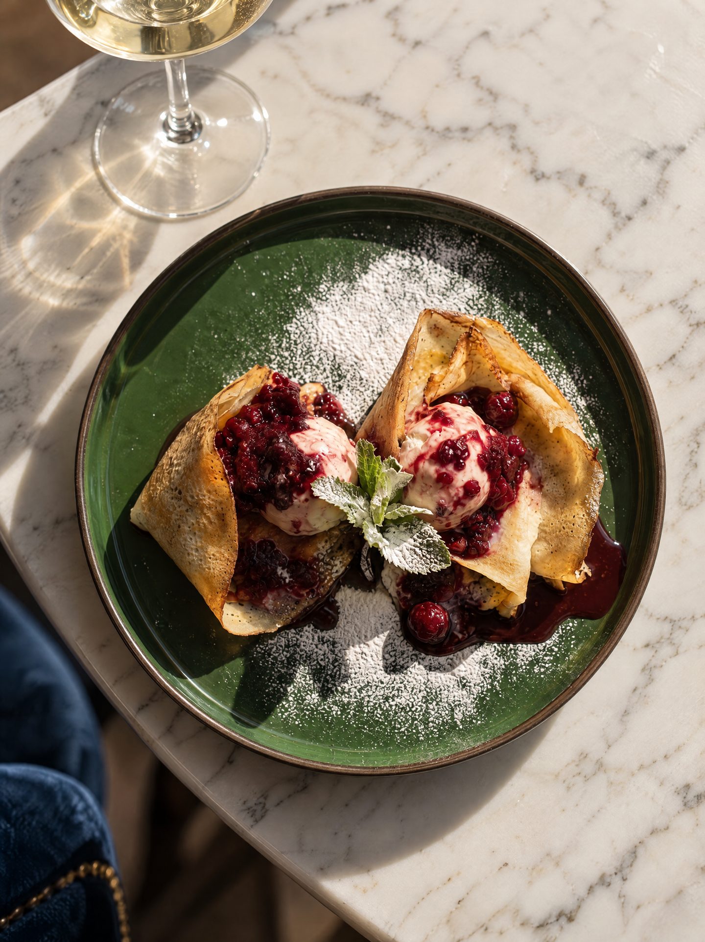 Pancakes folded around ice cream and berries, dusted with sugar