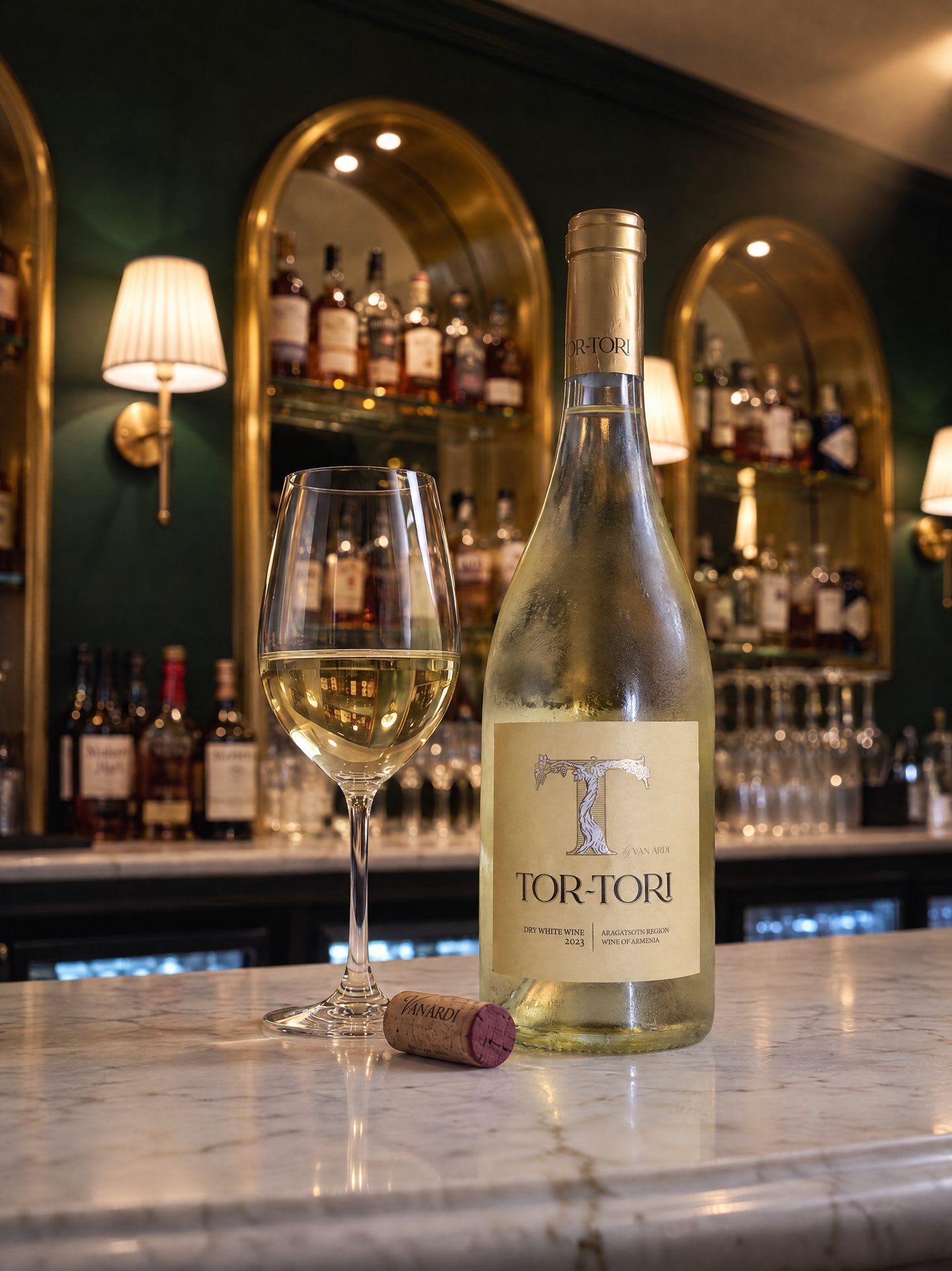 A bottle of Tor-Tori white wine beside a poured glass on the marble bar