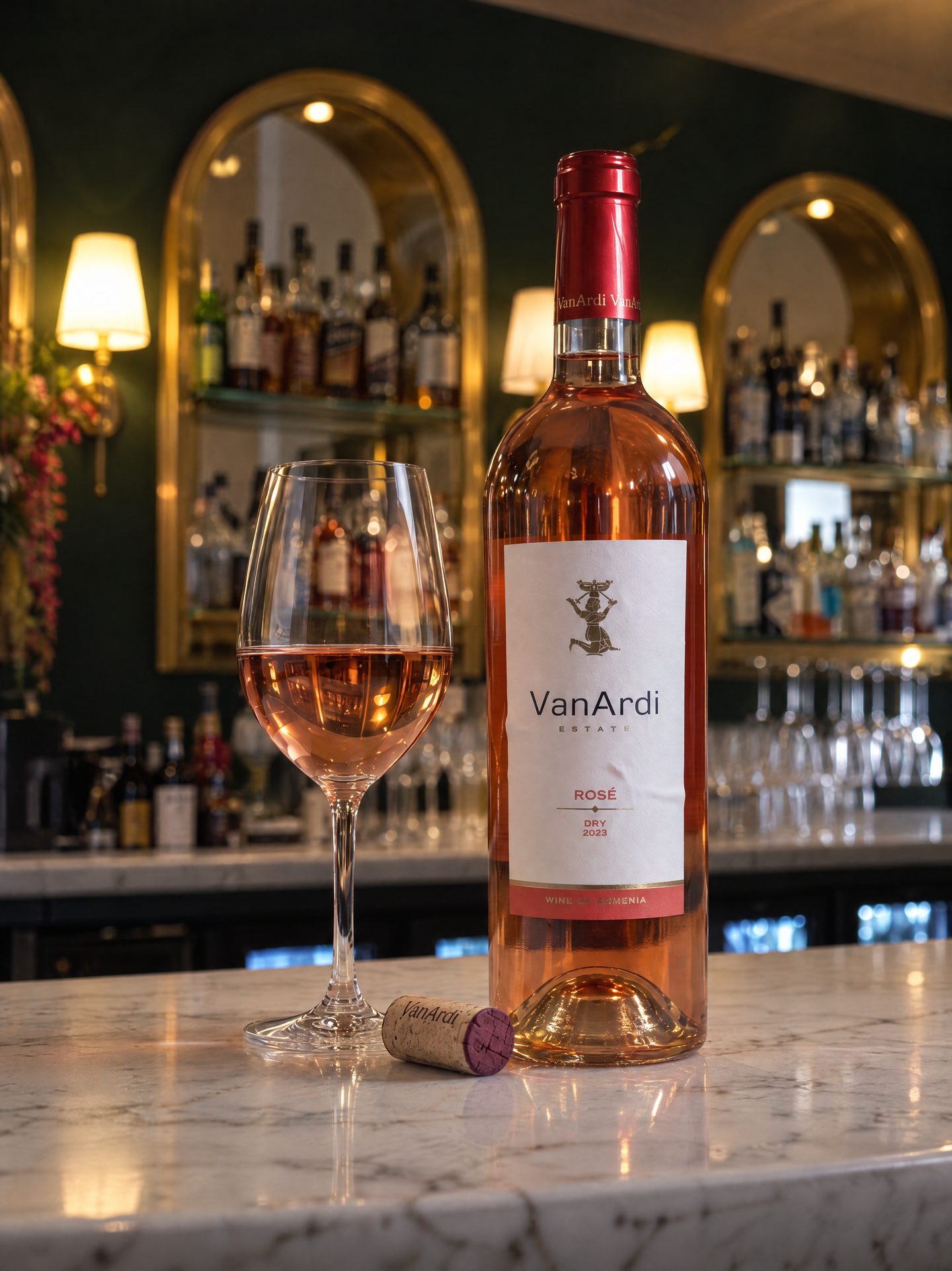 A bottle of Van Ardi rosé beside a poured glass on the marble bar