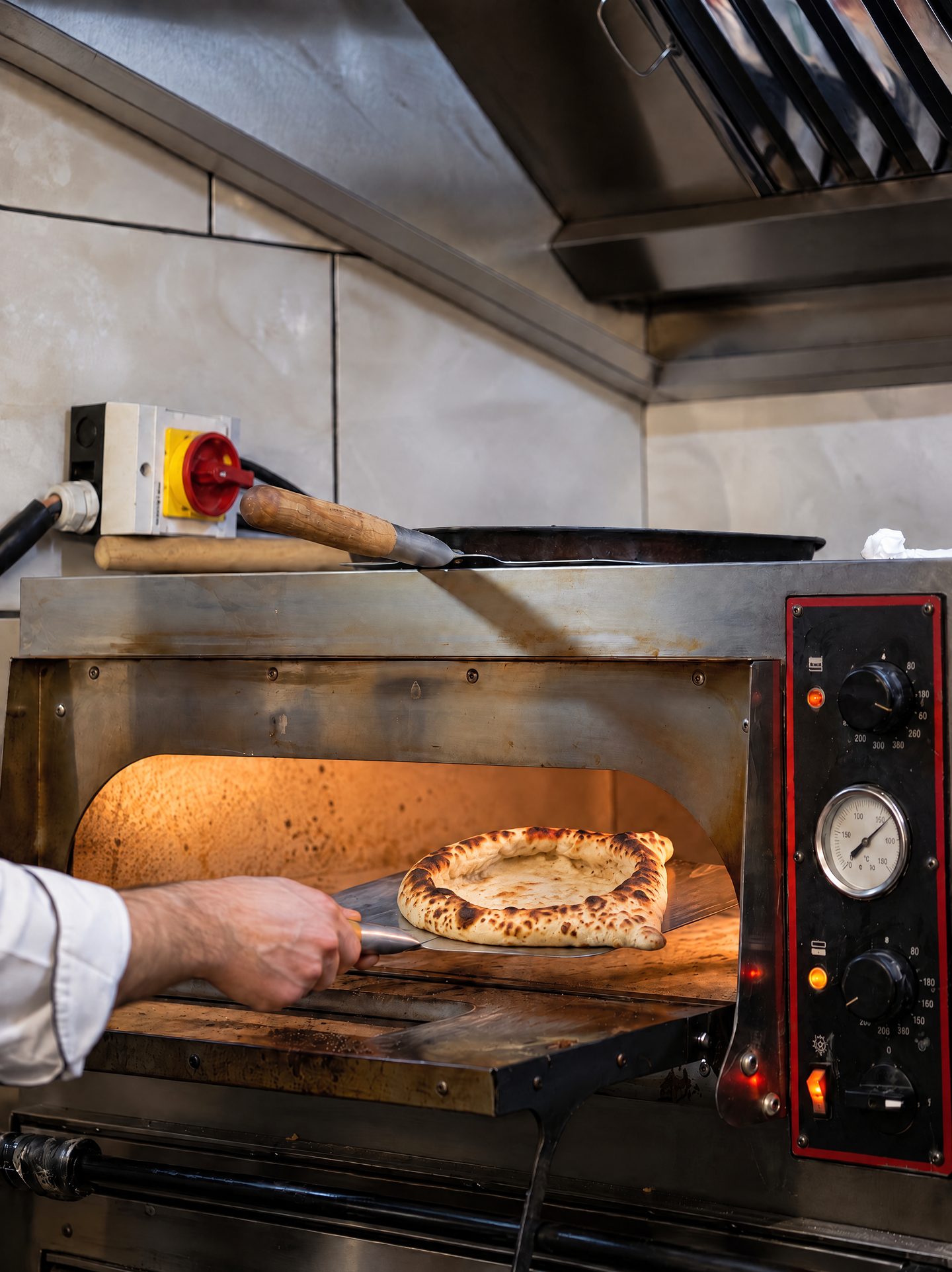 A cook lifting freshly baked bread out of the oven